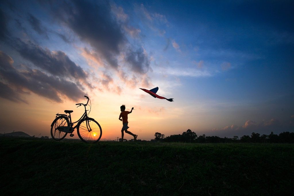 Silhouette of boy running with a kite.